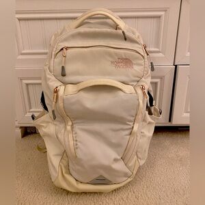 The North Face backpack in cream and gold.